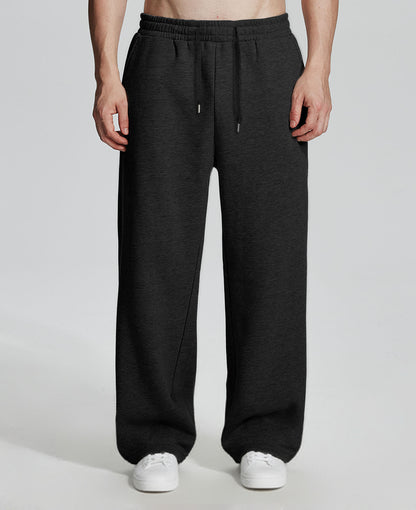 Model in black Men's Fleece Sweatpants ¨C Wide Leg Heavyweight Lounge Pants with white sneakers, showing drape and relaxed fit.