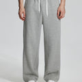 Model in light grey Men's Fleece Sweatpants ¨C Wide Leg Heavyweight Lounge Pants with white sneakers, showing drape and relaxed fit.