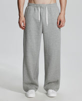 Model in light grey Men's Fleece Sweatpants ¨C Wide Leg Heavyweight Lounge Pants with white sneakers, showing drape and relaxed fit.