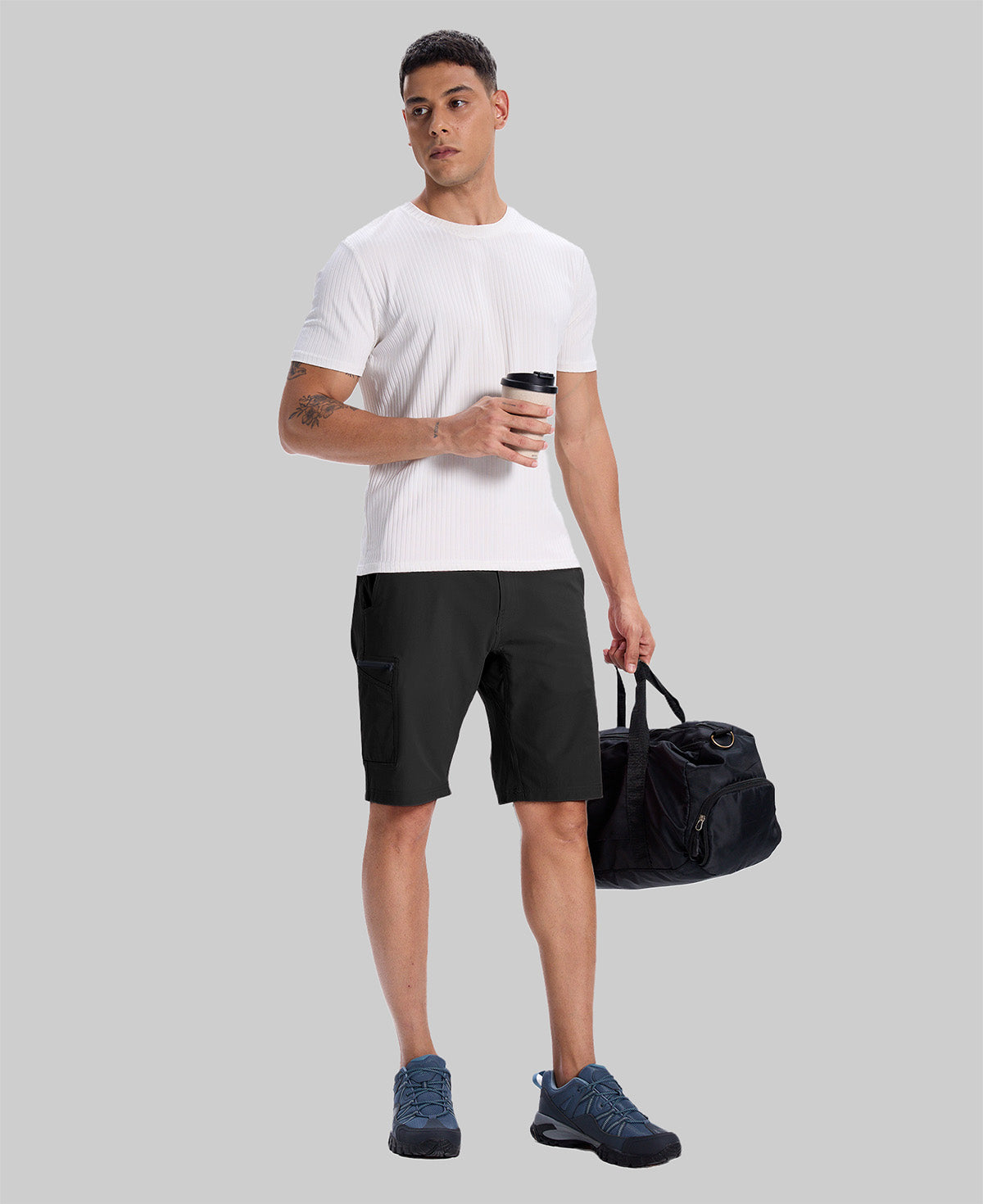 Model in white tee, black Men's Golf & Hiking Shorts, and blue-gray sneakers with coffee cup¡ªshowing casual wear styling.