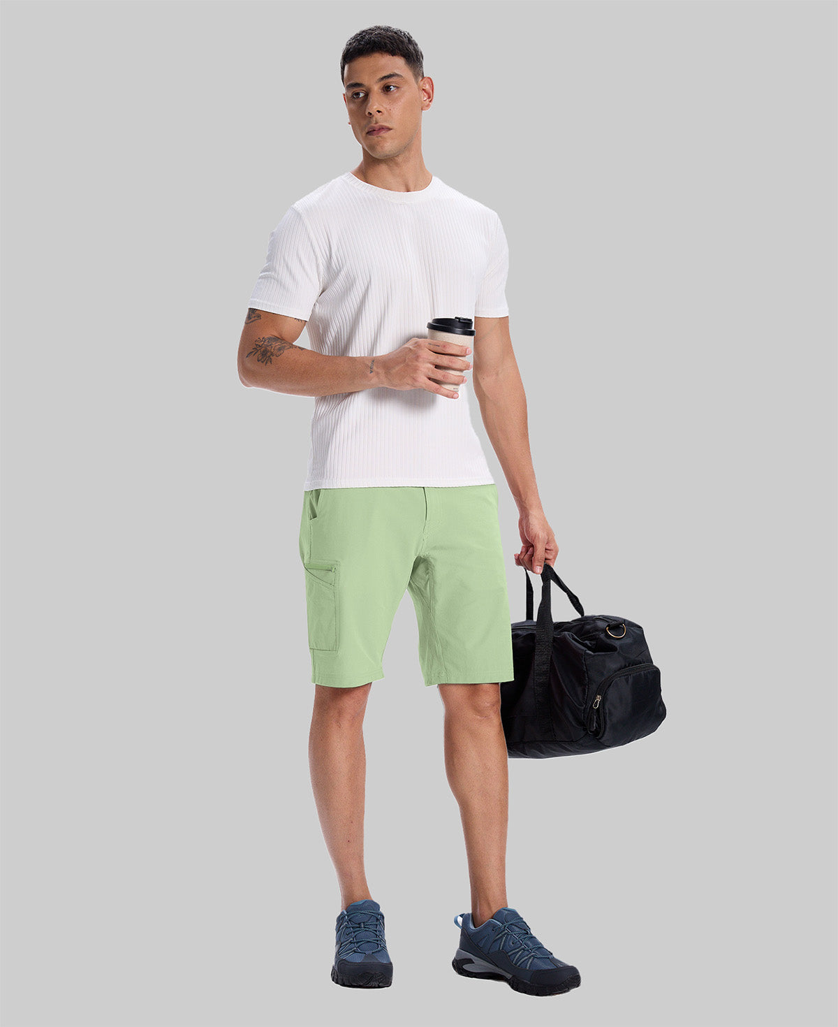 Model in white tee, light green Men's Golf & Hiking Shorts, and blue-gray sneakers with coffee cup¡ªshowing casual wear styling.