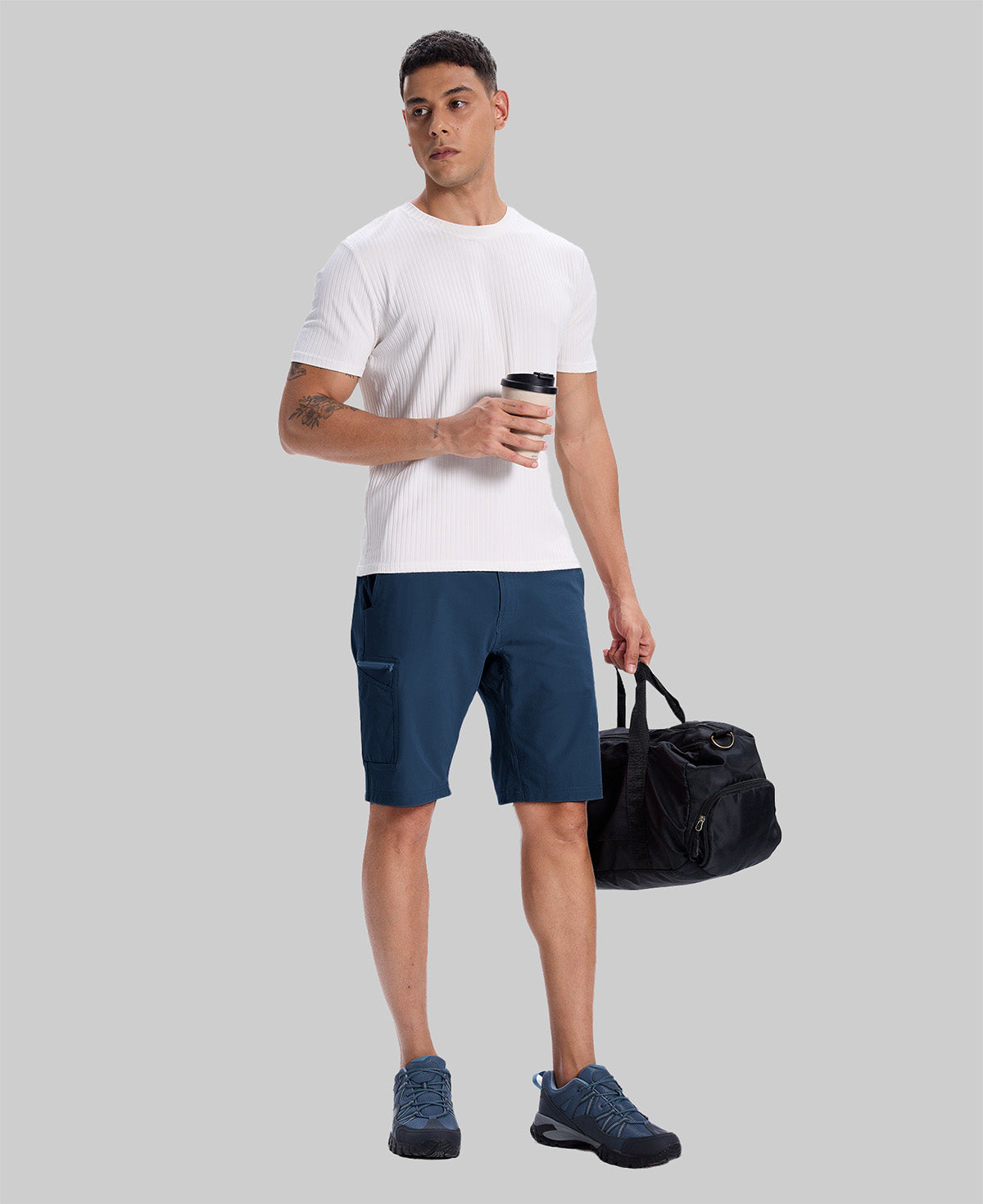 Model in white tee, navy blue Men's Golf & Hiking Shorts, and blue-gray sneakers with coffee cup¡ªshowing casual wear styling.