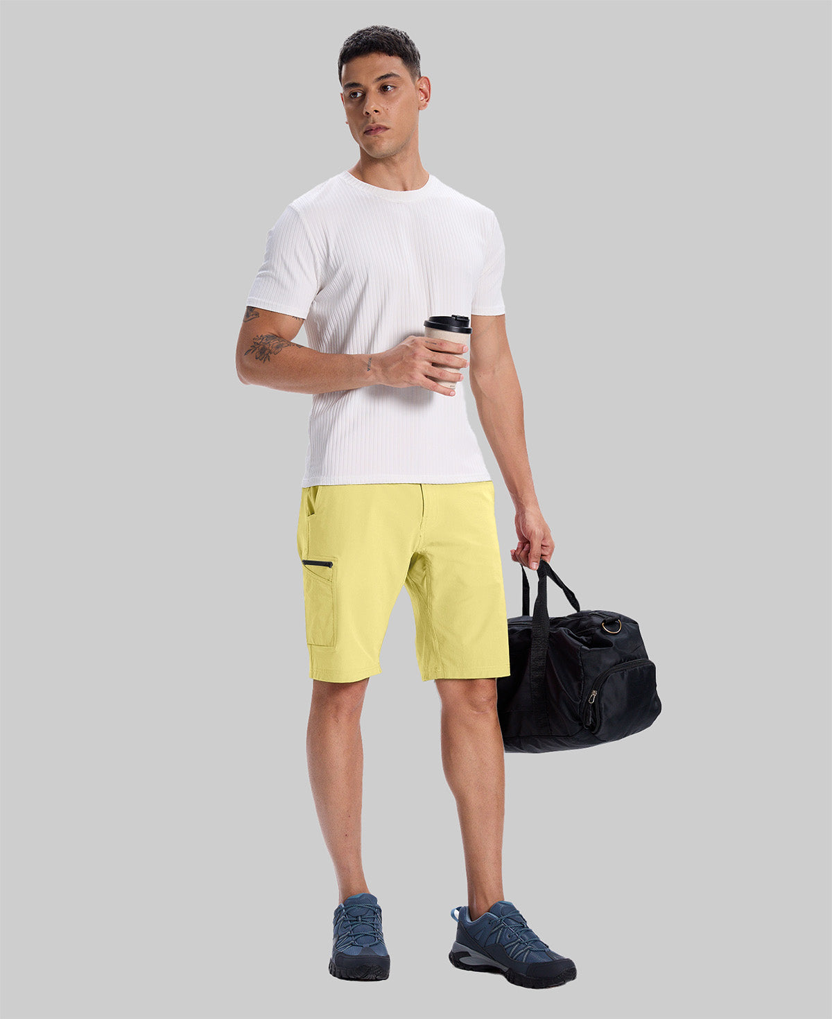 Model in white tee, light yellow Men's Golf & Hiking Shorts, and blue-gray sneakers with coffee cup¡ªshowing casual wear styling.