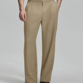 Man in beige sweater, beige Gurkha pants & brown shoes, hand in pocket showing pleated wide leg drape and flow.