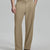Man in beige sweater, beige Gurkha pants & brown shoes, hand in pocket showing pleated wide leg drape and flow.