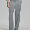 Man in beige sweater, grey Gurkha pants & brown shoes, hand in pocket showing pleated wide leg drape and flow.