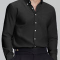 Man in black Men's Oxford Button Down Dress Shirt ¨C Wrinkle Resistant, with matching trousers and hand in pocket.