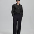 Full outfit: black Oxford shirt, wide-leg dress pants & brown shoes, minimalist yet polished style.