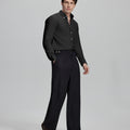Side profile of model in black Oxford shirt and trousers, clean lines and sharp silhouette.