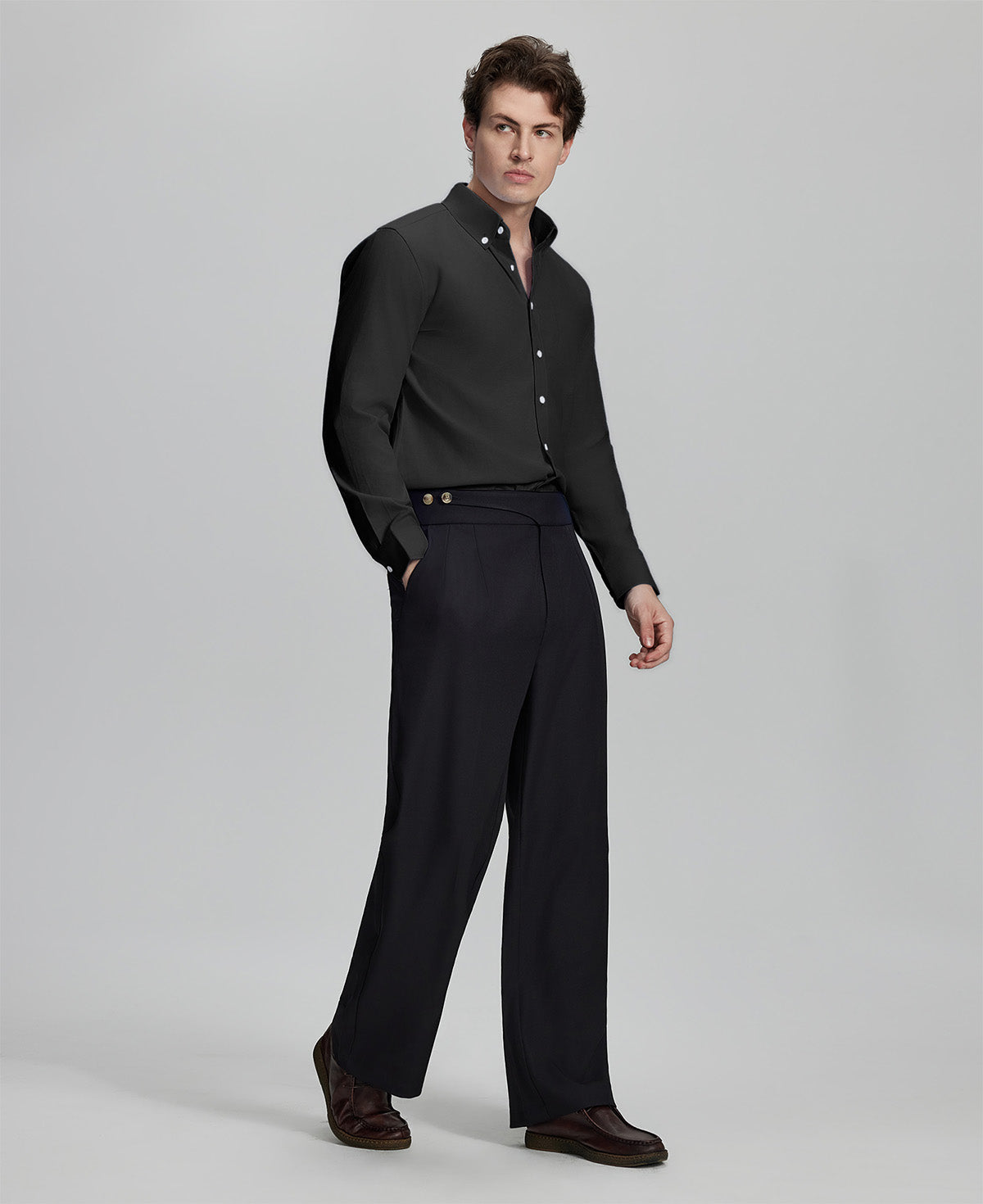 Side profile of model in black Oxford shirt and trousers, clean lines and sharp silhouette.