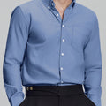 Man in deep blue Men's Oxford Button Down Dress Shirt ¨C Wrinkle Resistant, with matching trousers and hand in pocket.