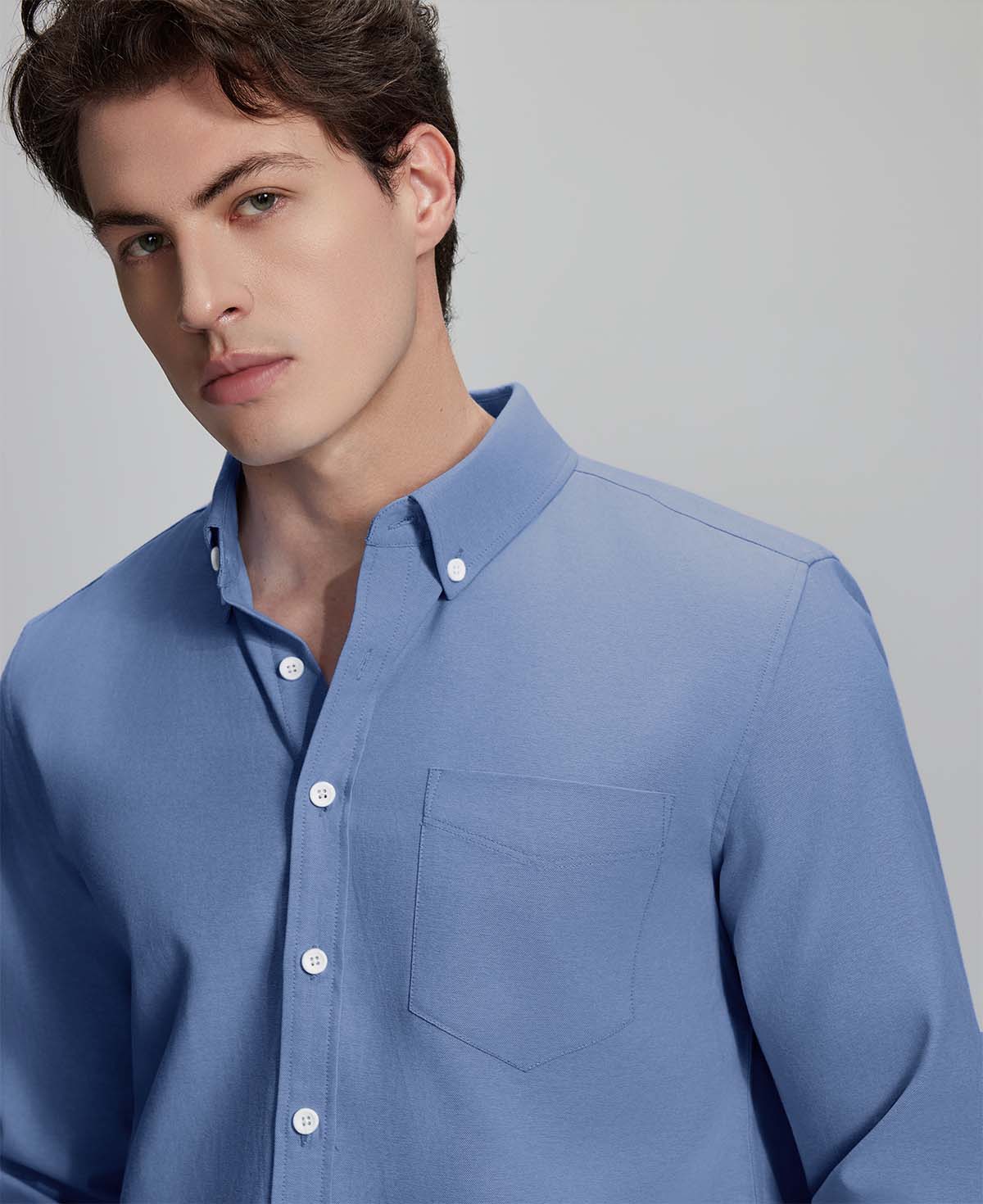 Close-up of placket, chest pocket, and buttons on wrinkle-resistant Oxford shirt, showing textured fabric quality.
