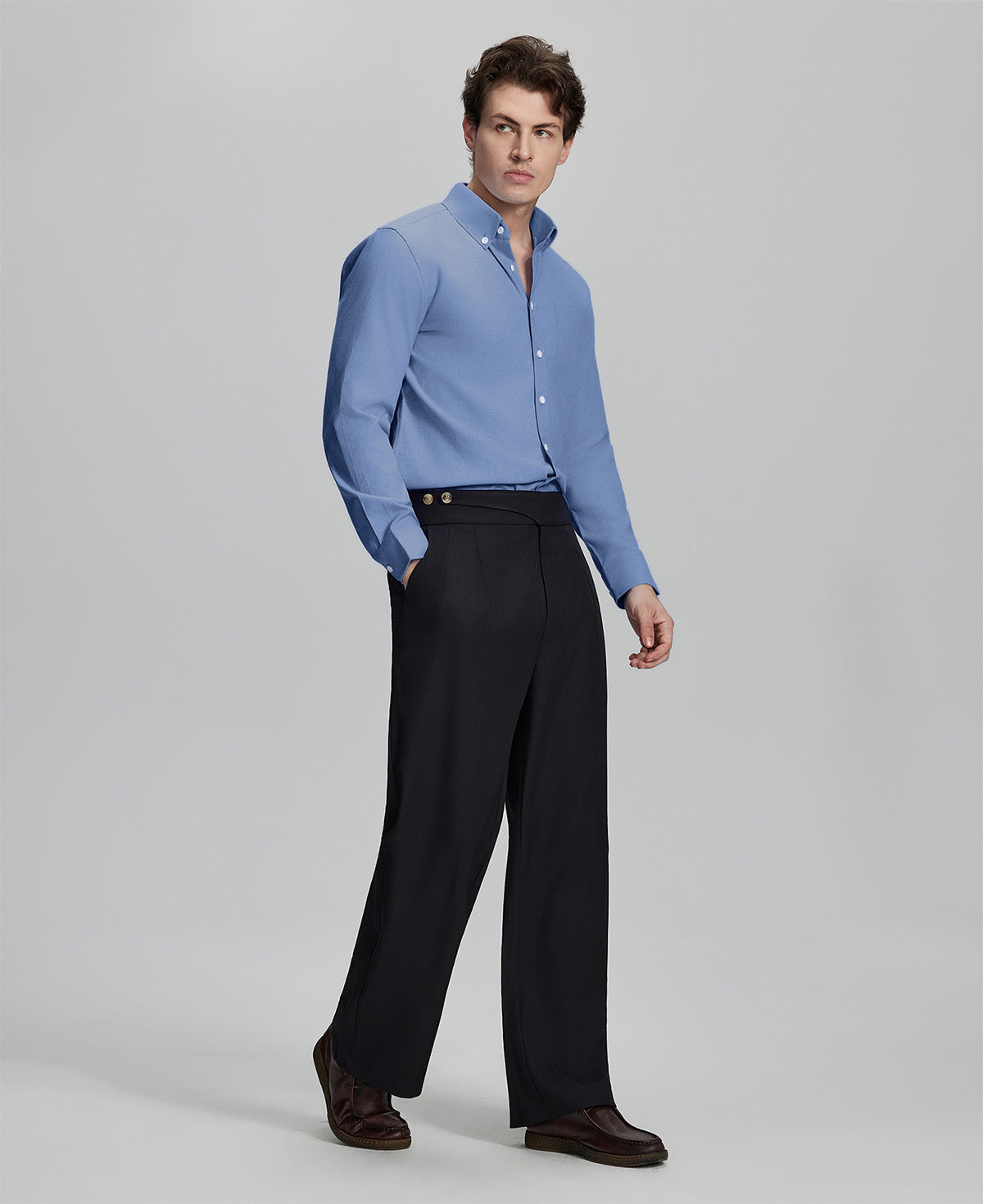 Side profile of model in deep blue Oxford shirt and trousers, clean lines and sharp silhouette.