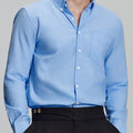 Man in light blue Men's Oxford Button Down Dress Shirt ¨C Wrinkle Resistant, with matching trousers and hand in pocket.
