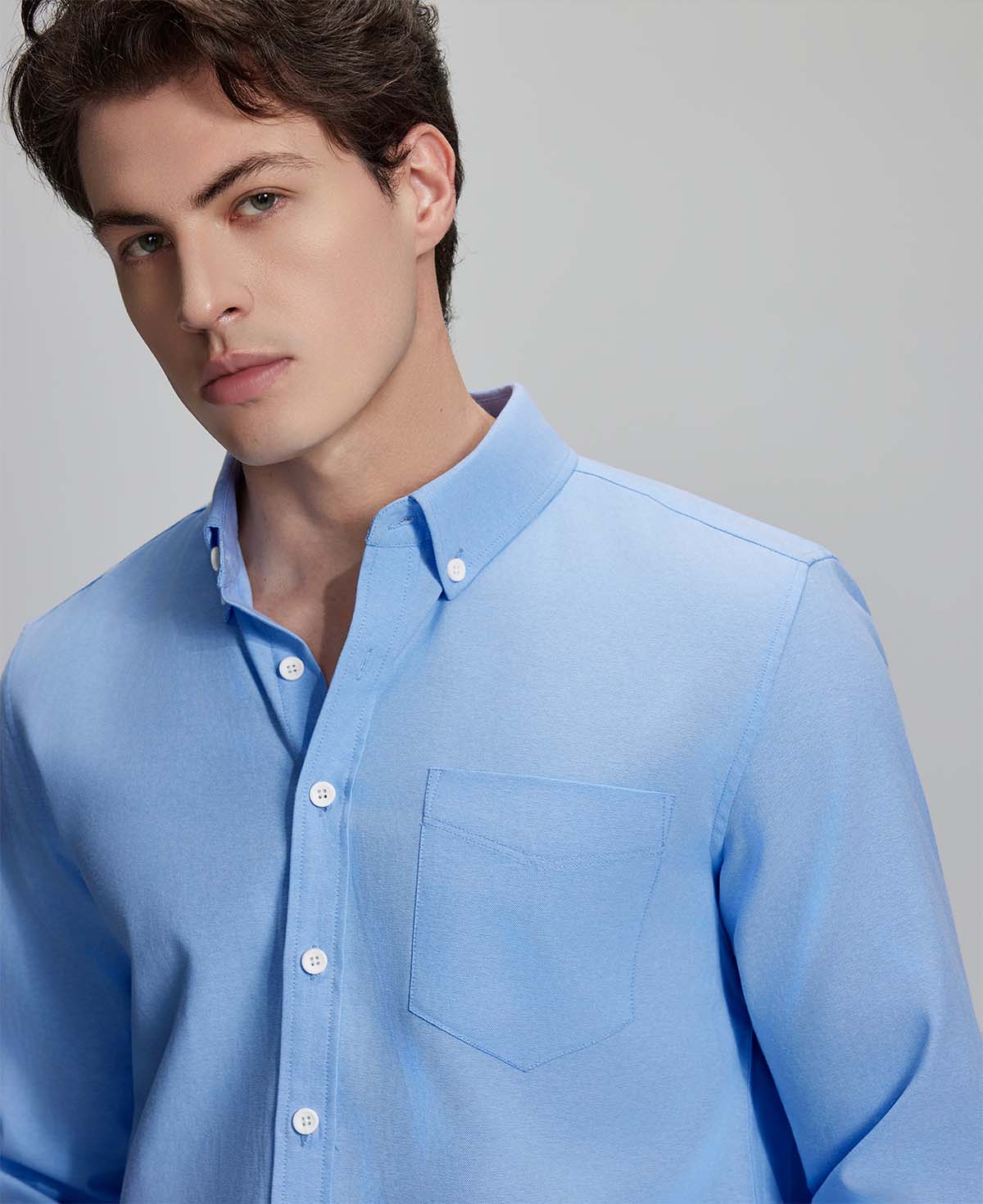 Close-up of placket, chest pocket, and buttons on wrinkle-resistant Oxford shirt, showing textured fabric quality.