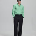 Full outfit: light green Oxford shirt, wide-leg dress pants & brown shoes, minimalist yet polished style.