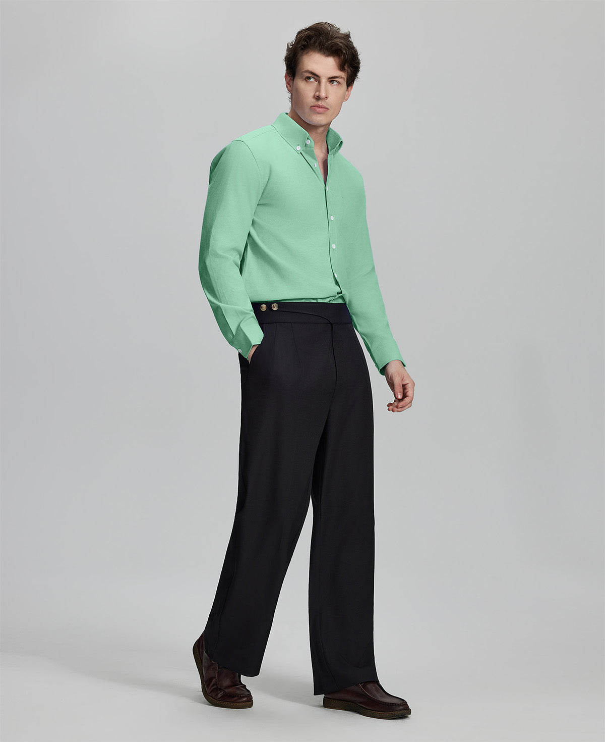 Side profile of model in light green Oxford shirt and trousers, clean lines and sharp silhouette.