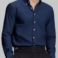 Man in navy blue Men's Oxford Button Down Dress Shirt ¨C Wrinkle Resistant, with matching trousers and hand in pocket.