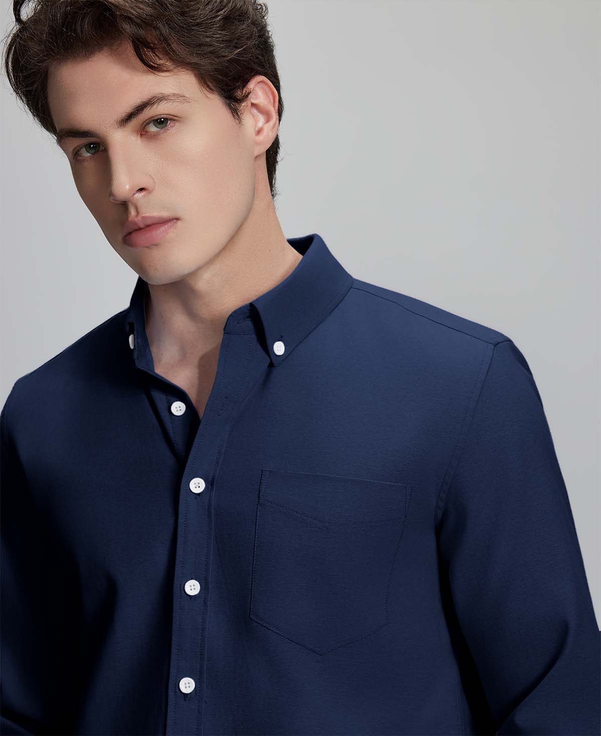 Close-up of placket, chest pocket, and buttons on wrinkle-resistant Oxford shirt, showing textured fabric quality.