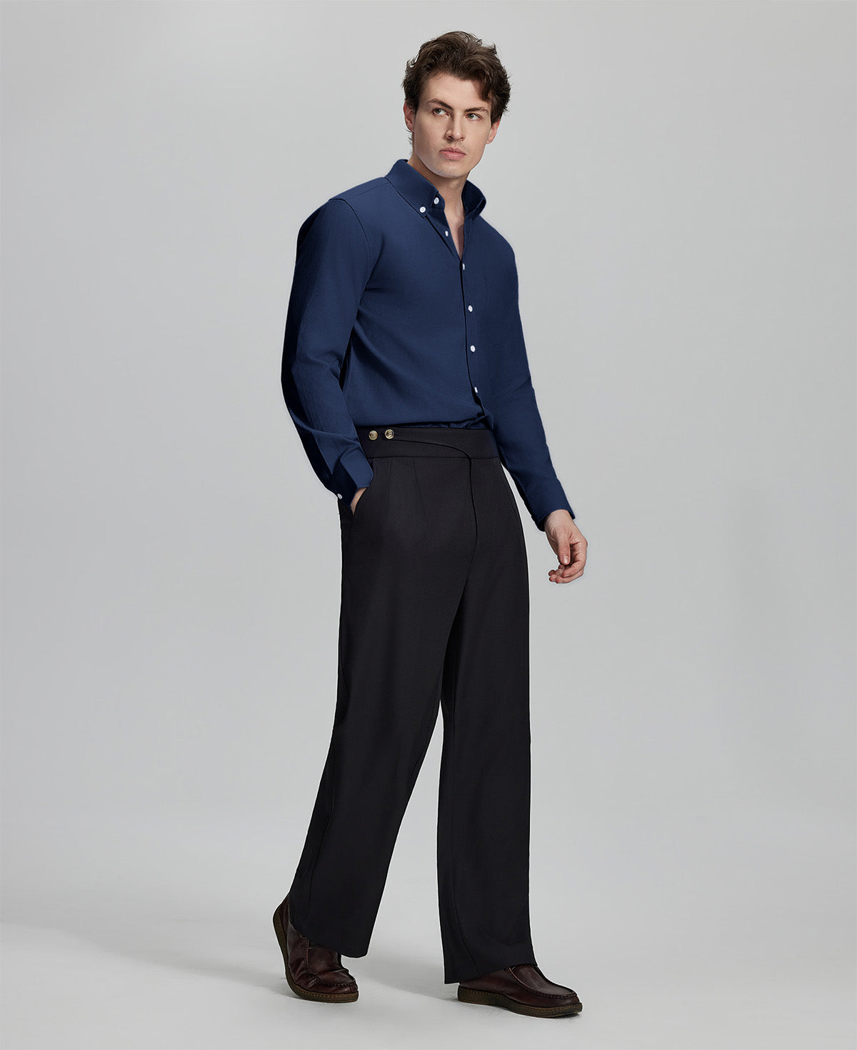 Side profile of model in navy blue Oxford shirt and trousers, clean lines and sharp silhouette.