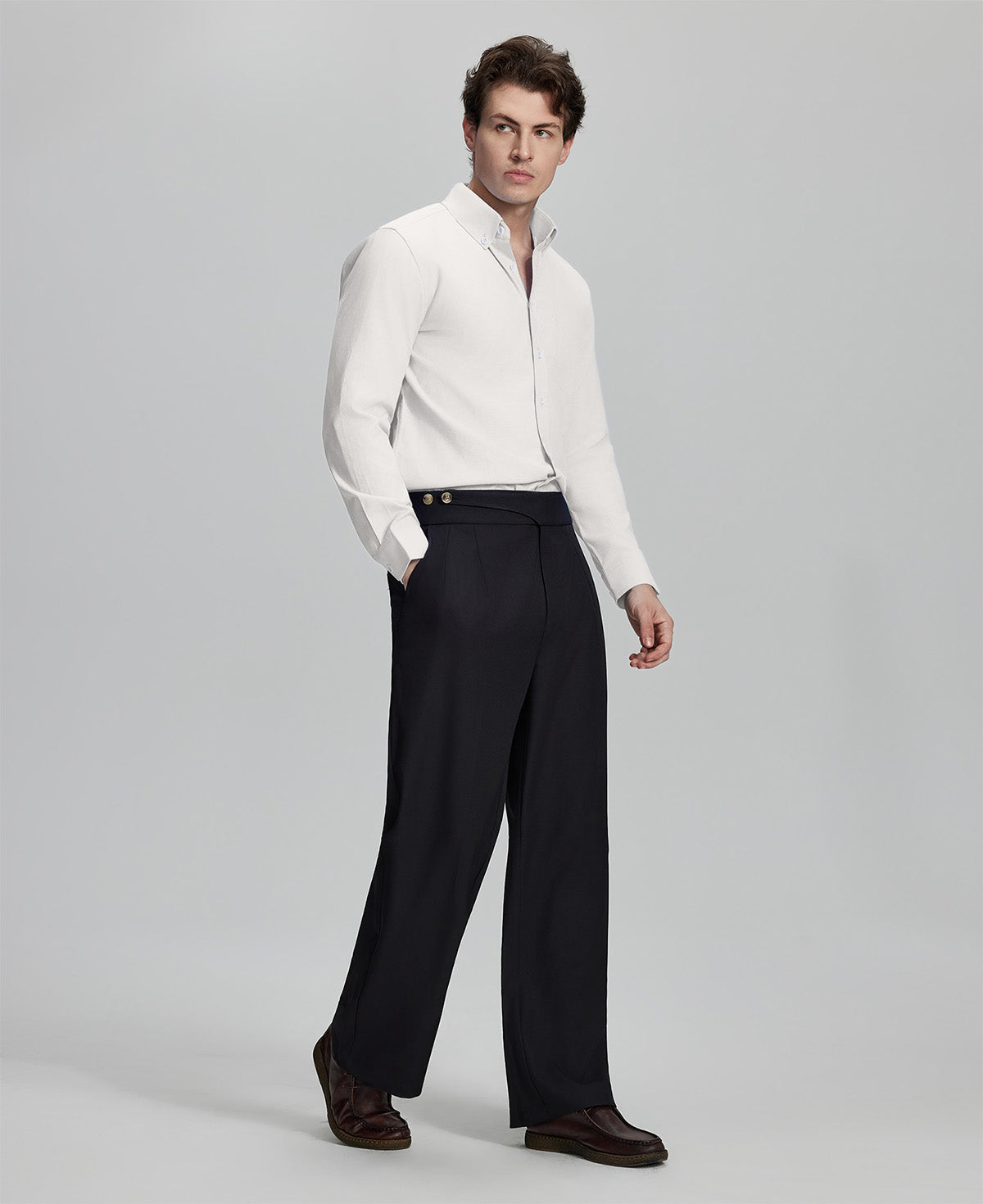 Side profile of model in white Oxford shirt and trousers, clean lines and sharp silhouette.