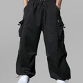 Man in black baggy sweatpants, high waist, five pockets, back logo. White sneakers, standing front.