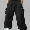 Man in black baggy sweatpants, high waist, five pockets, back logo. White sneakers, standing front.