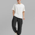Full view of man wearing black baggy sweatpants with white tee and sneakers, highlighting fit.