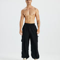 Bare-chested man in black baggy sweatpants, white shoes, highlighting waist and length details.
