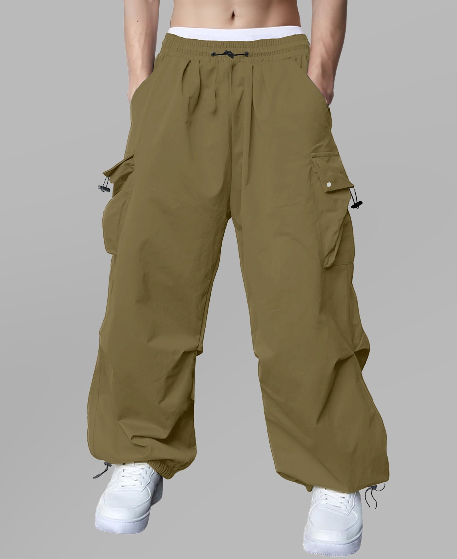 Man in brown baggy sweatpants, high waist, five pockets, back logo. White sneakers, standing front.