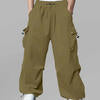 Man in brown baggy sweatpants, high waist, five pockets, back logo. White sneakers, standing front.