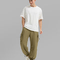 Full view of man wearing brown baggy sweatpants with white tee and sneakers, highlighting fit.