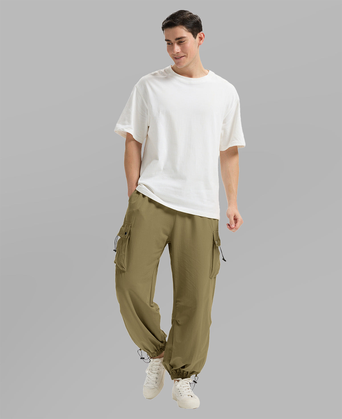 Full view of man wearing brown baggy sweatpants with white tee and sneakers, highlighting fit.