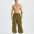 Bare-chested man in brown baggy sweatpants, white shoes, highlighting waist and length details.