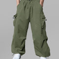 Man in light green baggy sweatpants, high waist, five pockets, back logo. White sneakers, standing front.