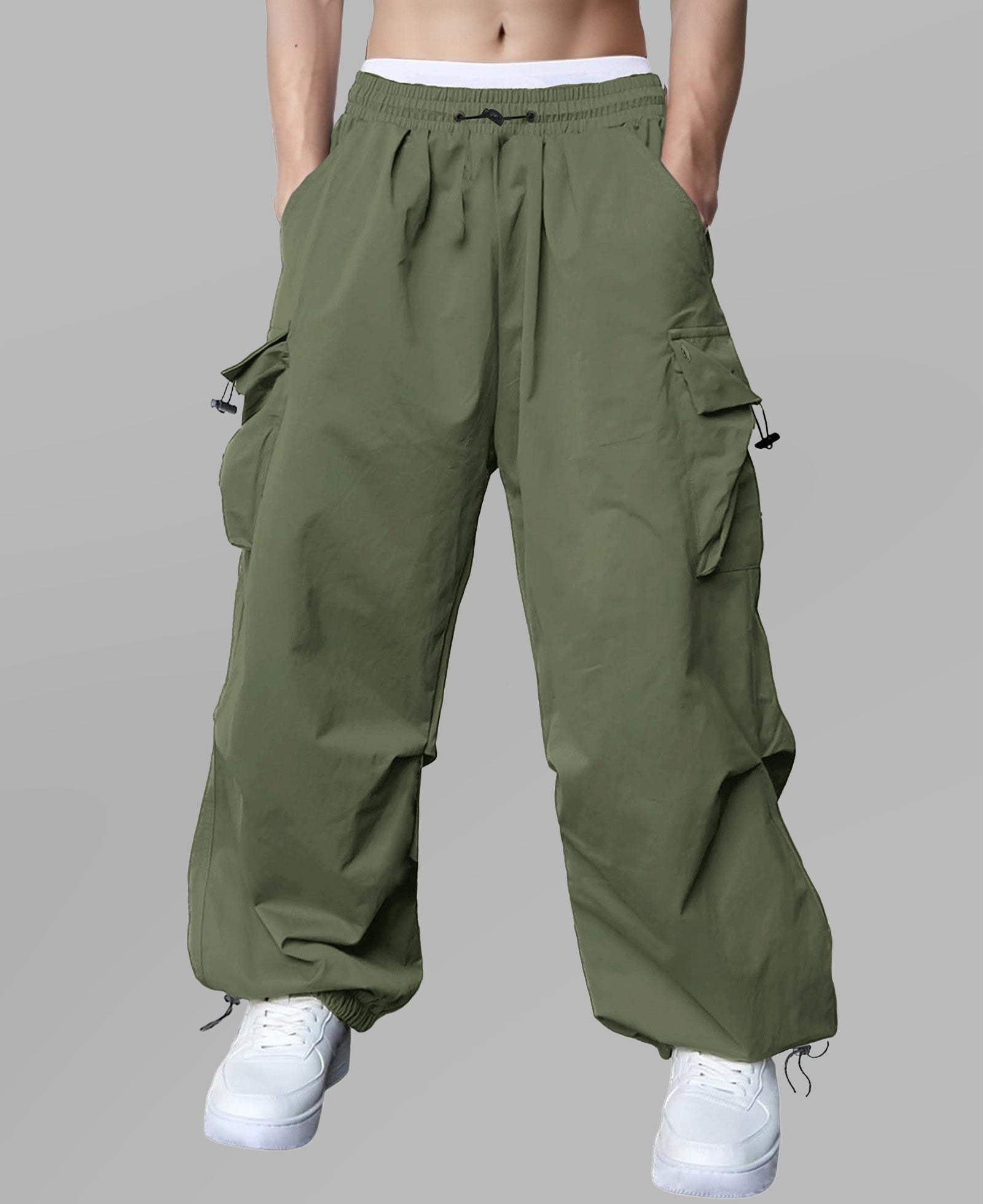 Man in light green baggy sweatpants, high waist, five pockets, back logo. White sneakers, standing front.