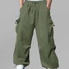 Man in light green baggy sweatpants, high waist, five pockets, back logo. White sneakers, standing front.