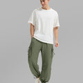 Full view of man wearing light green baggy sweatpants with white tee and sneakers, highlighting fit.
