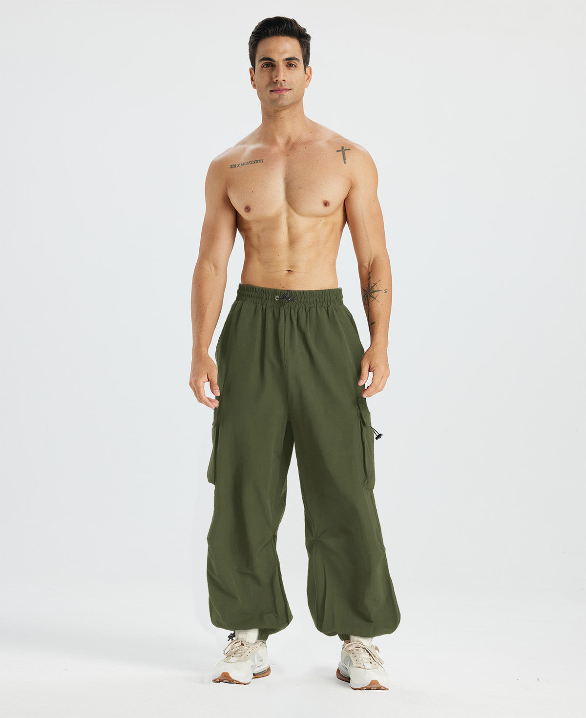 Bare-chested man in light green baggy sweatpants, white shoes, highlighting waist and length details.
