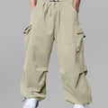 Man in khaki baggy sweatpants, high waist, five pockets, back logo. White sneakers, standing front.