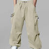 Man in khaki baggy sweatpants, high waist, five pockets, back logo. White sneakers, standing front.