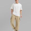 Full view of man wearing khaki baggy sweatpants with white tee and sneakers, highlighting fit.