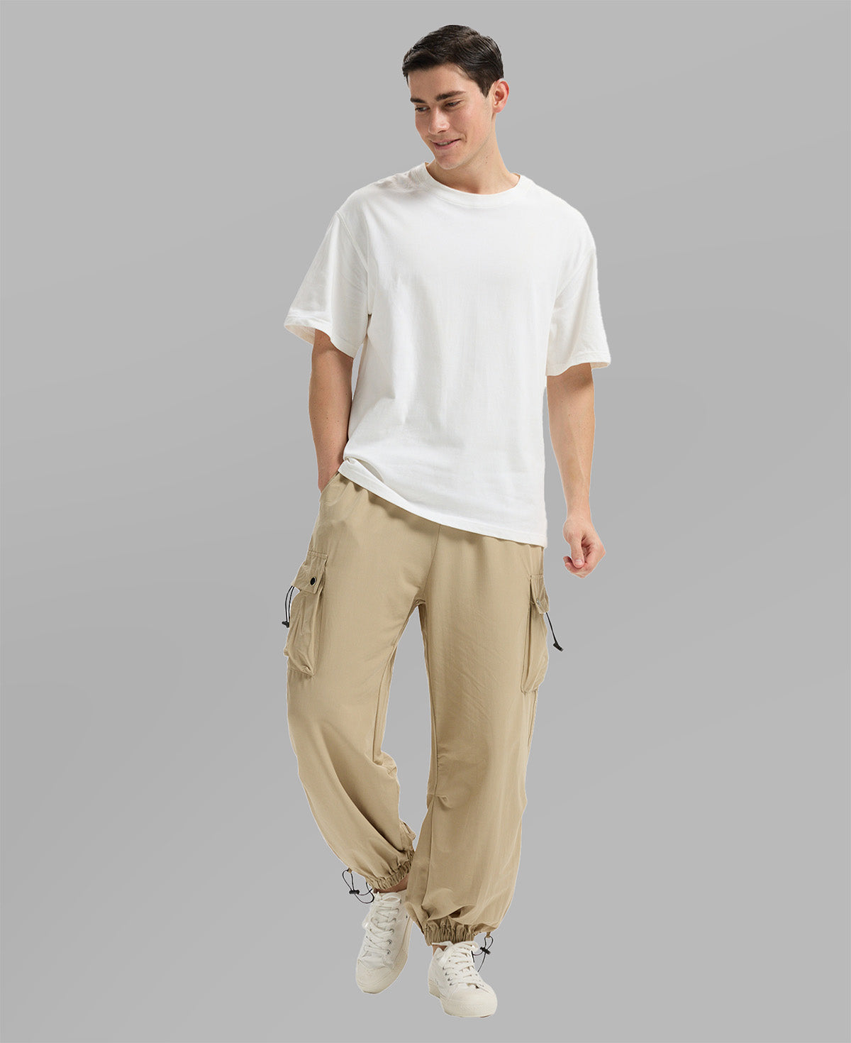 Full view of man wearing khaki baggy sweatpants with white tee and sneakers, highlighting fit.