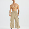 Bare-chested man in khaki baggy sweatpants, white shoes, highlighting waist and length details.