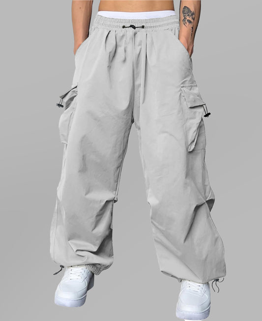Man in light grey baggy sweatpants, high waist, five pockets, back logo. White sneakers, standing front.