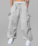 Man in light grey baggy sweatpants, high waist, five pockets, back logo. White sneakers, standing front.