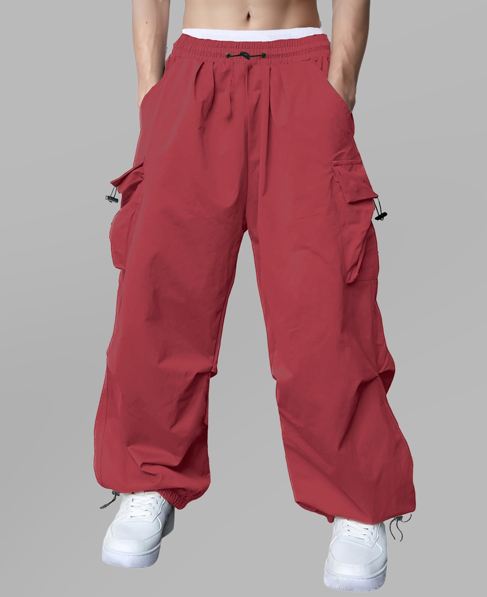 Man in red baggy sweatpants, high waist, five pockets, back logo. White sneakers, standing front.
