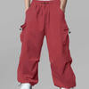 Man in red baggy sweatpants, high waist, five pockets, back logo. White sneakers, standing front.
