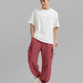 Full view of man wearing red baggy sweatpants with white tee and sneakers, highlighting fit.