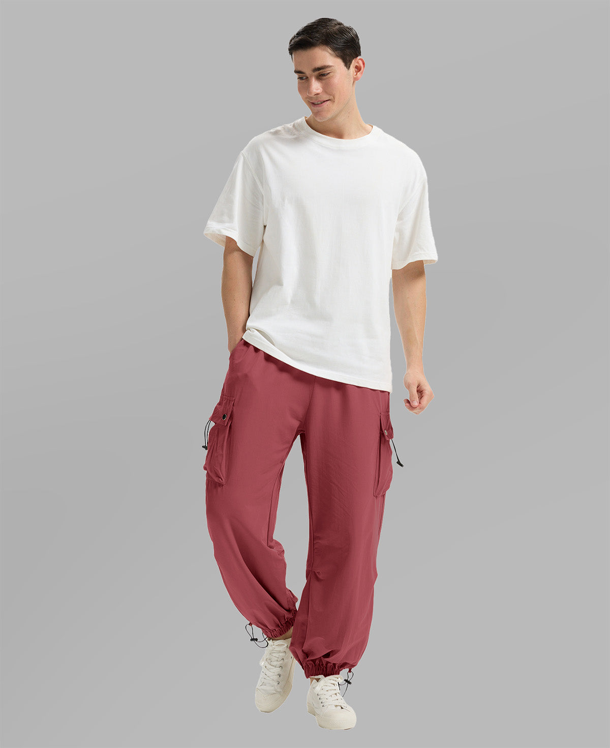 Full view of man wearing red baggy sweatpants with white tee and sneakers, highlighting fit.